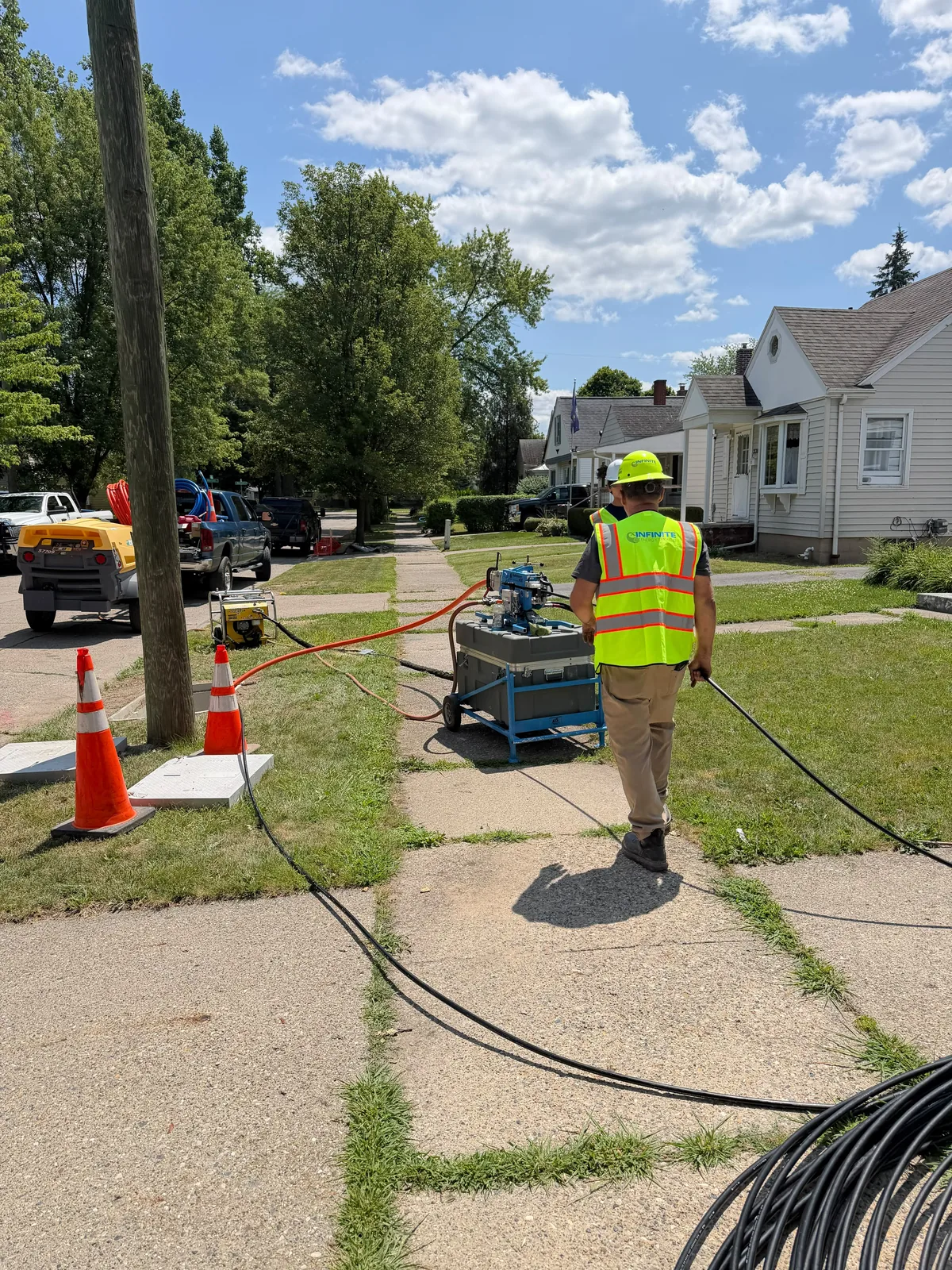 Infinite Energy Services technician walking cable down the sidewalk during fiber placement
