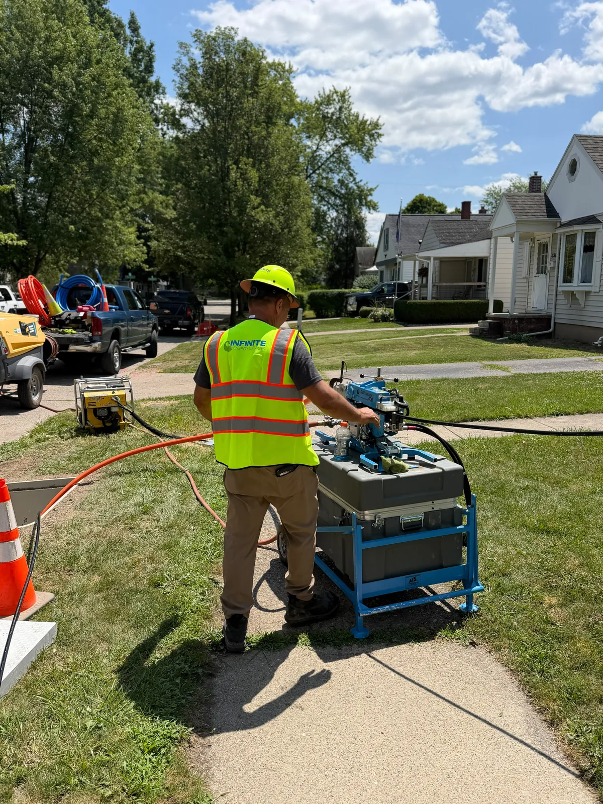 Infinite Energy Services technician running a fiber jetting / blowing machine on a residential street